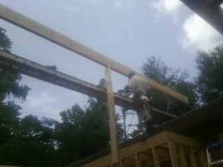 Carpenter setting a ridge beam over a new addition frame — Ice Dam Removal by Roofing Brothers in Paint Bank
