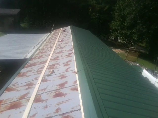 Old rusted panels beside newly installed green metal roofing — Wind Damage Roof Repair by Roofing Brothers in Paint Bank