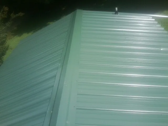 New green metal panels meeting at the ridge of a roof — Flat Roof Repair work by our crew in Paint Bank