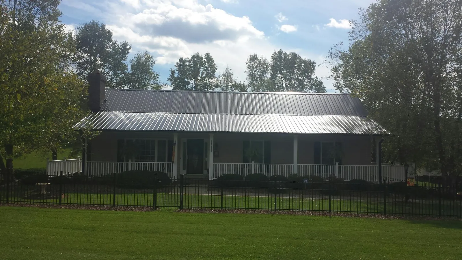 Gray metal roof on a brick ranch with a full width front porch — Gutter Guard Installation work by our crew in Paint Bank