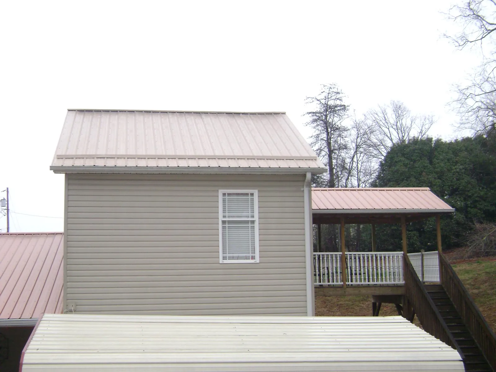 Tan metal roofs on a two story addition and attached porch, from a Roof Replacement job in Paint Bank