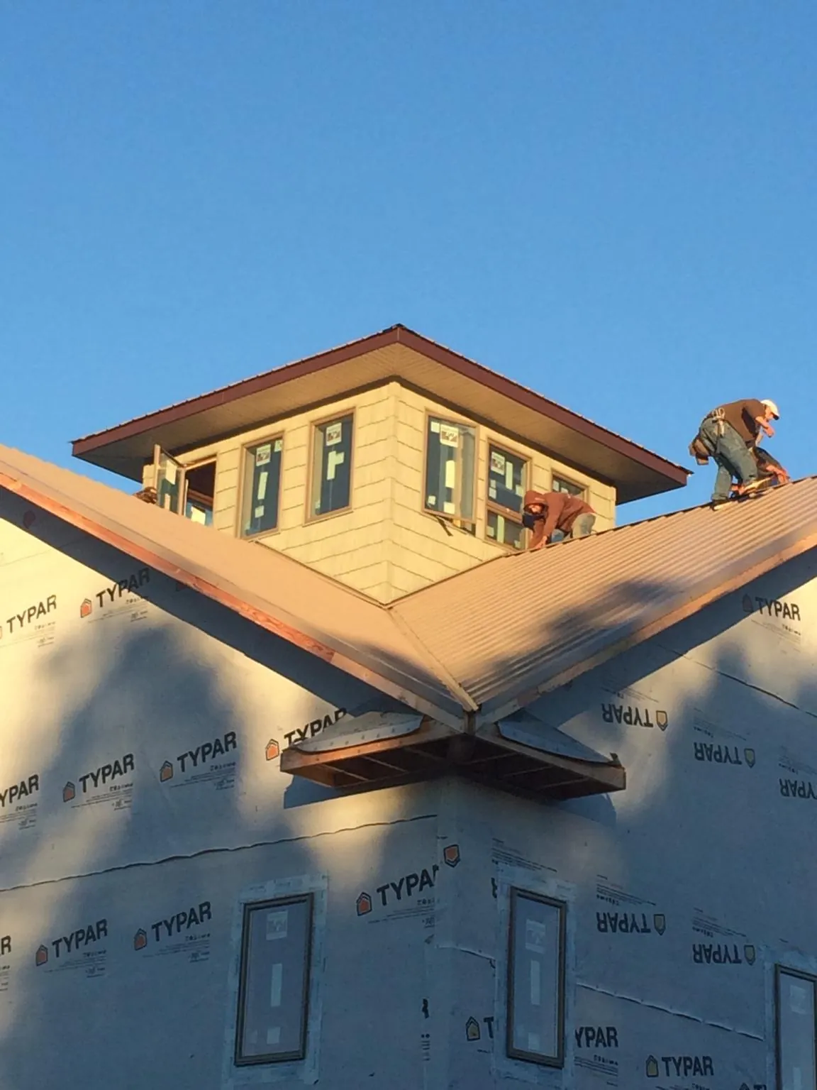Roofers working around a rooftop cupola on a new metal roof at sunset — Roof Waterproofing in Paint Bank by Roofing Brothers